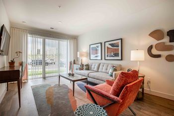 A living room with a couch and a chair and a window